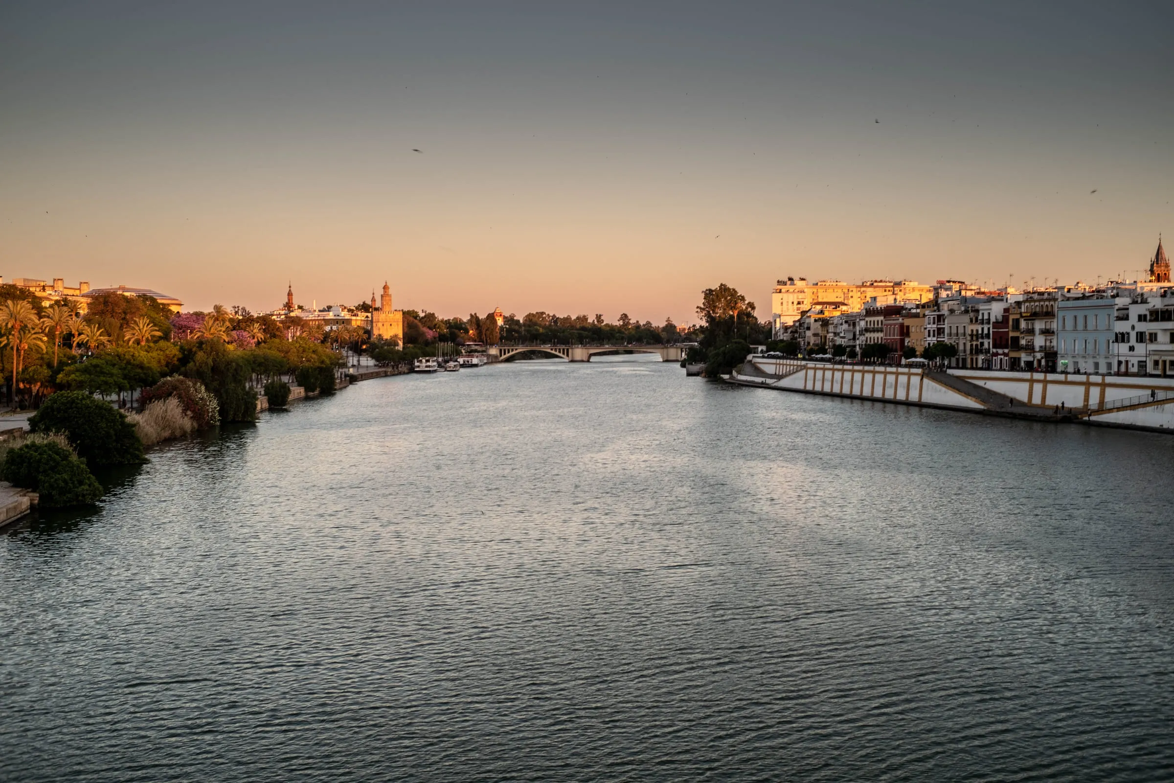 The canal at sunset with the city on both banks and a footbridge crossing in the distance