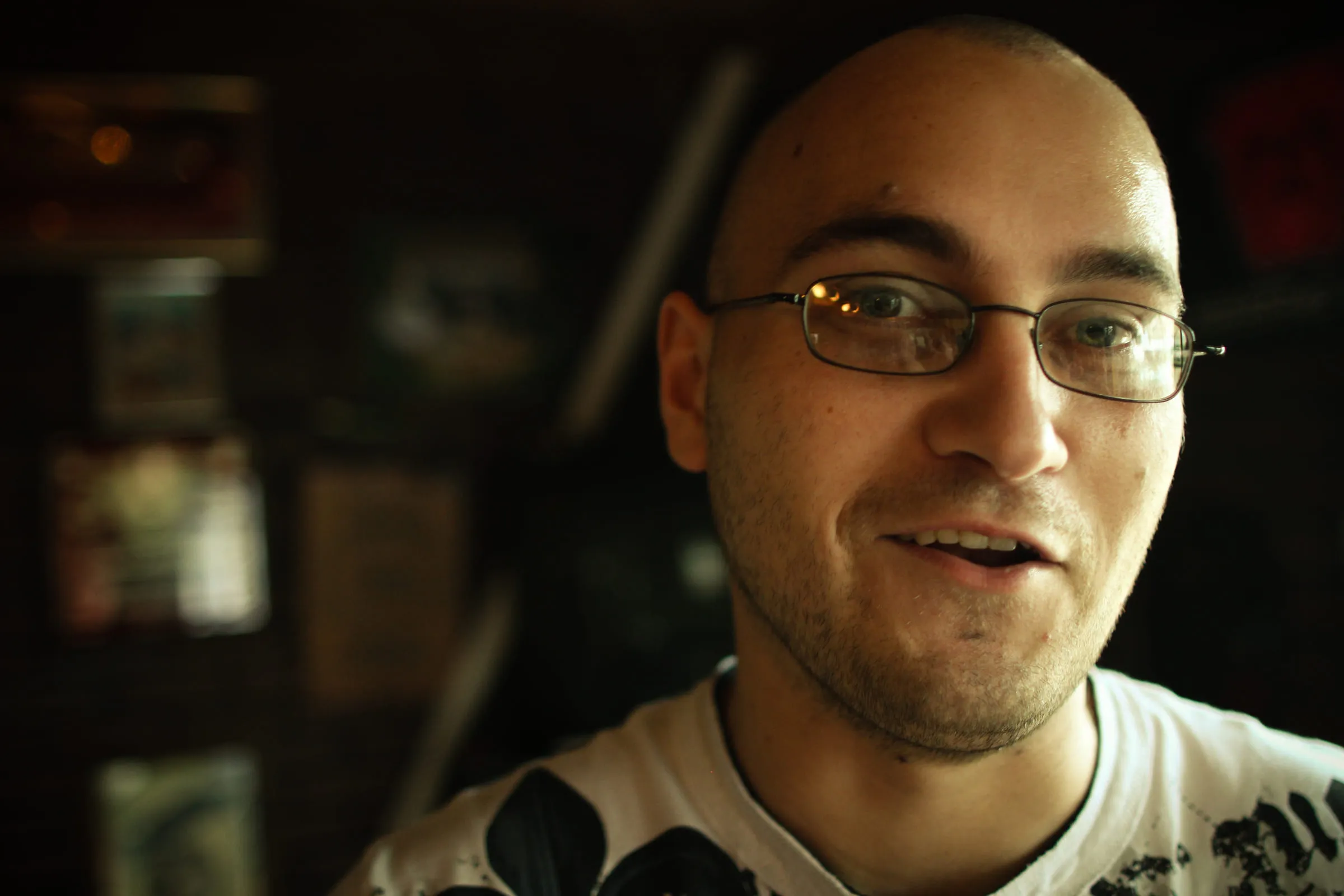 Portrait of David in glasses, mid-sentence, in a dim warmly lit room