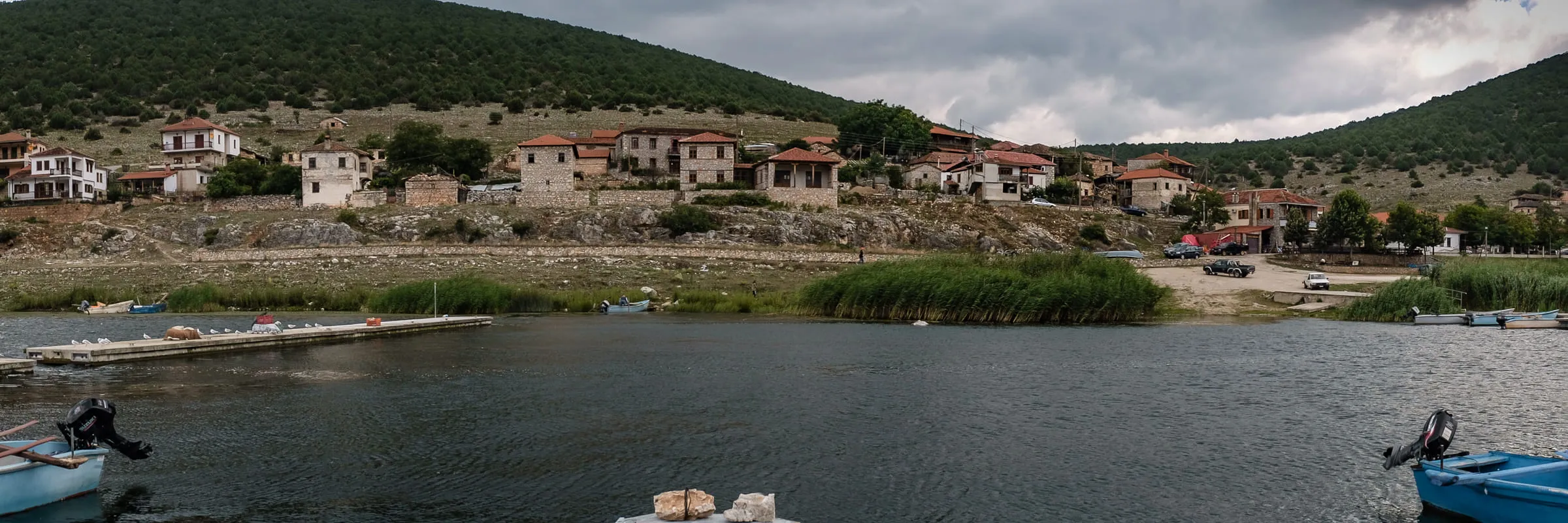 The village of Psarades along the lakeshore, small blue fishing boats drawn up in the foreground