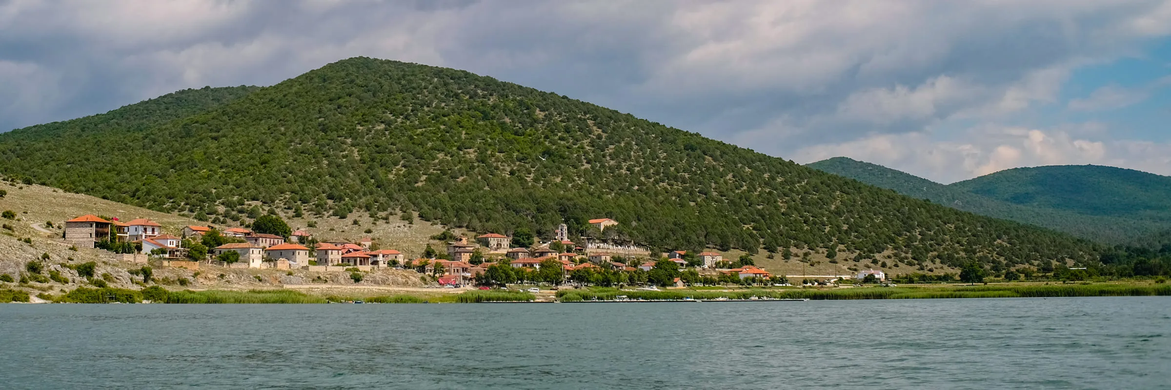 Psarades seen from across the water, the village small beneath a large forested hill